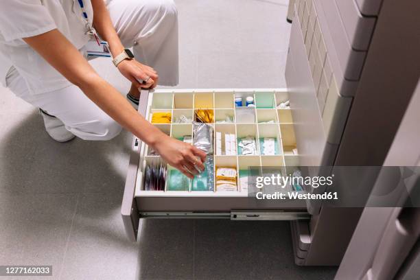 female doctor searching medicines in drawer at pharmacy - kabinet stockfoto's en -beelden