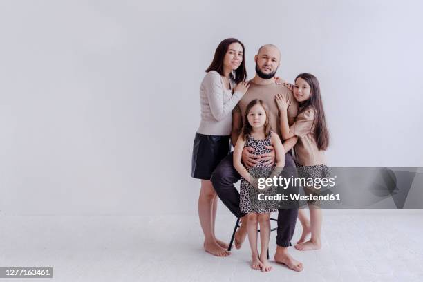 mother and daughter embracing father sitting on chair at studio - quartet stock pictures, royalty-free photos & images