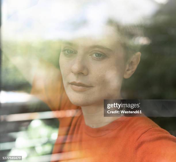 close-up of thoughtful mid adult woman at home seen through window - woman day dreaming stockfoto's en -beelden