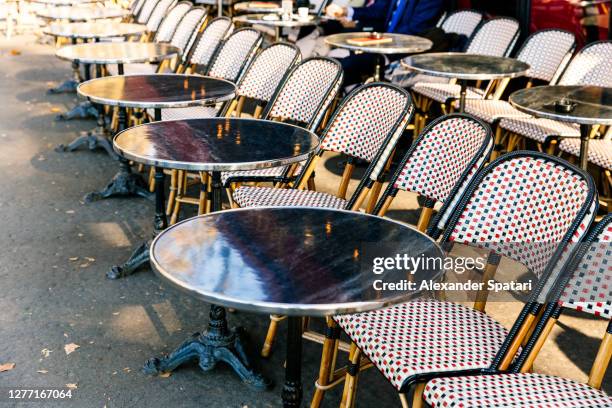 empty tables and chairs at an outdoors sidewalk cafe in paris, france - frans terras stockfoto's en -beelden