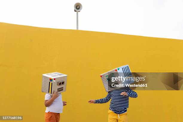 friends wearing robot costumes standing against yellow wall - robot costume stock-fotos und bilder