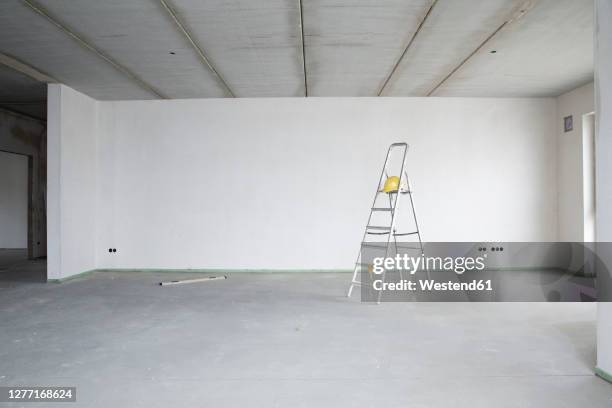ladder with hardhat against wall in renovating house - apartment no furniture stockfoto's en -beelden