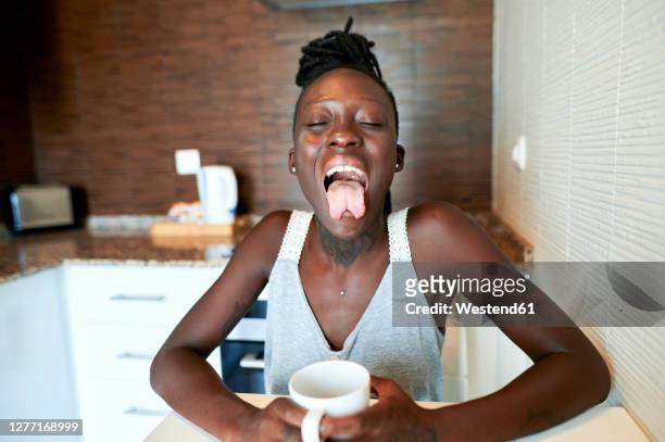 hipster woman with forked tongue having coffee in kitchen - gespleten tong stockfoto's en -beelden