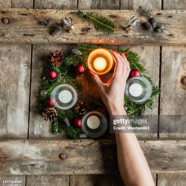 hand of woman touching glass cover of candle burning on advent wreath - advent kerze stock-fotos und bilder