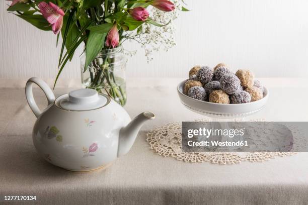 jar with blooming flowers, bowl of protein balls and white ceramic teapot - doily stock pictures, royalty-free photos & images