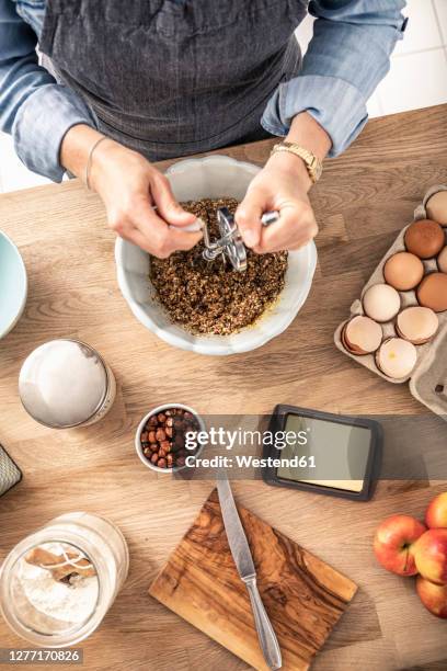 woman mixing batter with egg beater while standing at kitchen island - stirring stock-fotos und bilder