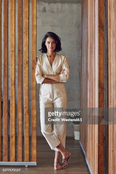 confident businesswoman with arms crossed standing at entrance of office - leaning stock pictures, royalty-free photos & images