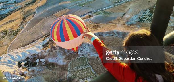 girl touches the hot air balloon with her finger, flying over spectacular cappadocia, turkey - cappadocia hot air balloon stock pictures, royalty-free photos & images
