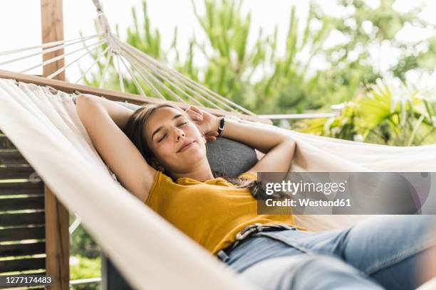 beautiful woman with arms raised napping on hammock in yard - hammock foto e immagini stock