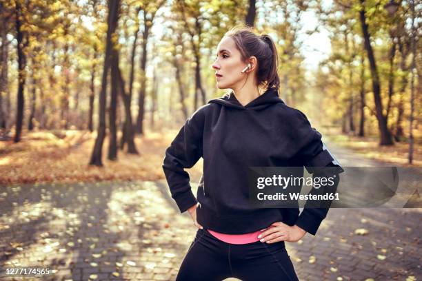 young female jogger during break looking sideways in autumn forest - hoodie imagens e fotografias de stock