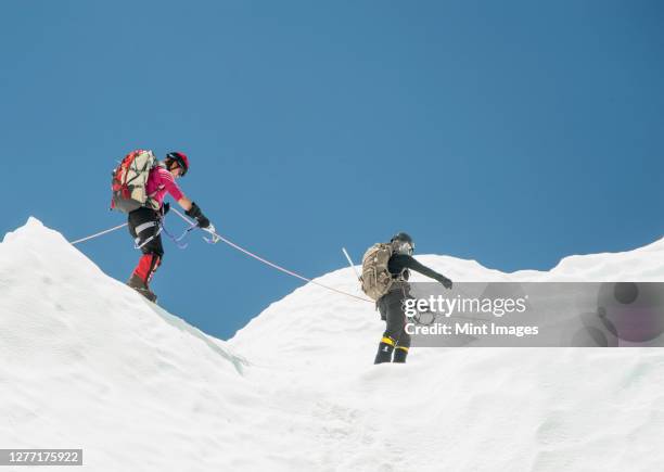 two climbers in snow on a mountain, roped together. - mt everest base camp stock pictures, royalty-free photos & images