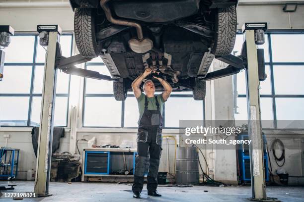 reifer mann arbeitet an einem fahrzeug in autowerkstatt - auto mechaniker stock-fotos und bilder