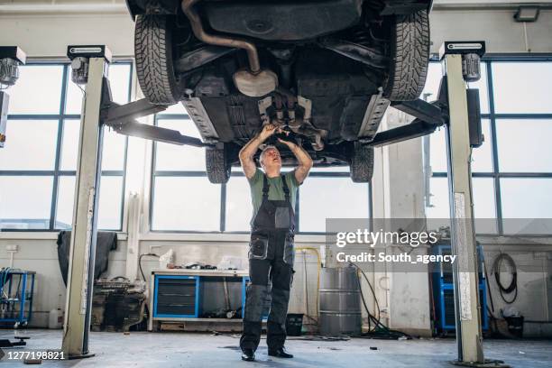 rijpe mens die aan een voertuig in autoreparatiewerkplaats werkt - auto mechanic stockfoto's en -beelden