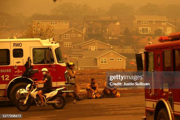 Redwood City firefighters take a break as they mop up hot spots at homes that were destroyed by the Glass Incident Fire on September 28, 2020 in...
