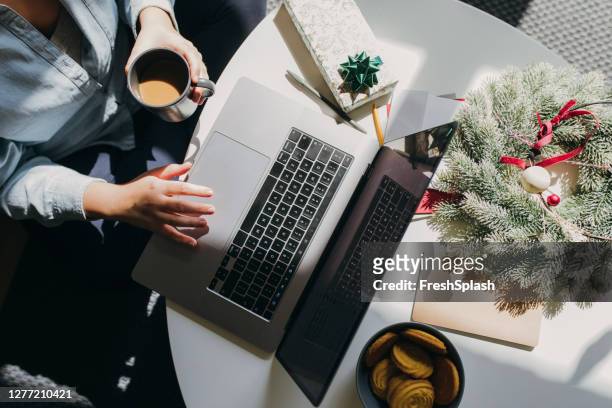 communicating with the loved ones on christmas: an anonymous woman using her laptop pc in a christmas setting - time off work stock pictures, royalty-free photos & images