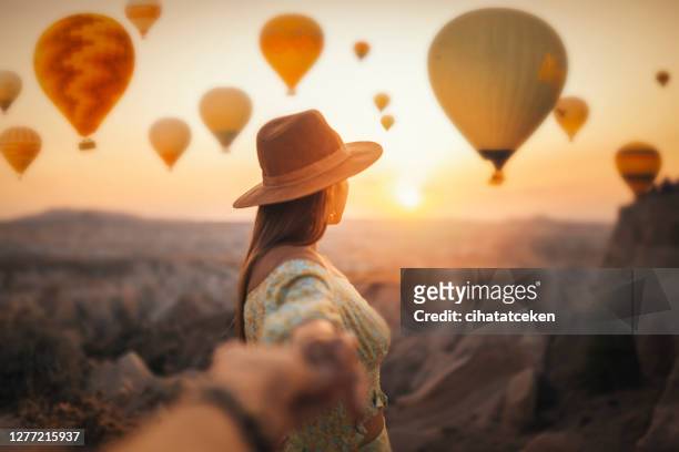 schöne frau beobachtet bunte heißluftballons fliegen über das tal bei kappadokien, türkei. türkei kappadokien märchenlandschaft der berge. folge mir - cappadocia hot air balloon stock-fotos und bilder