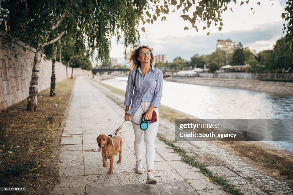 Schöne Frau zu Fuß ihren Hund am Fluss