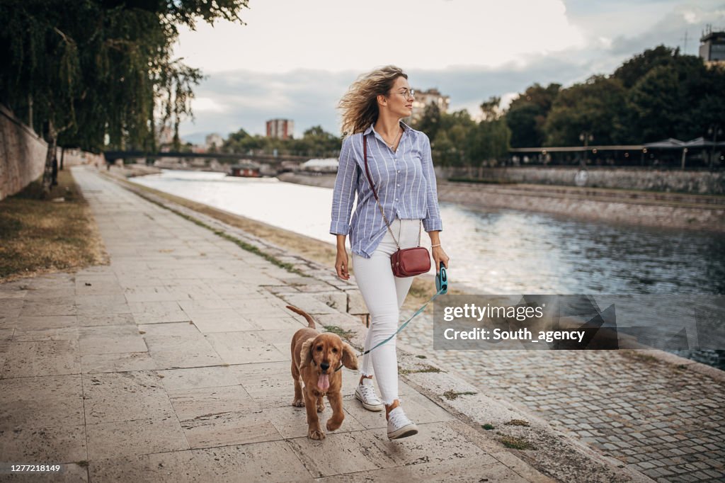 Mooie vrouw die haar hond door de rivier loopt