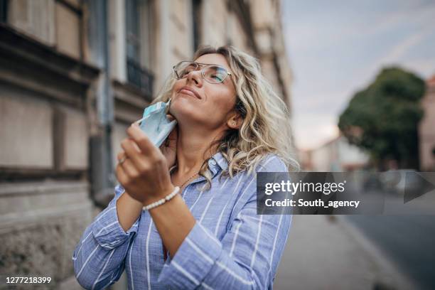 beautiful woman taking off protective mask on face on the street - taking off glasses stock pictures, royalty-free photos & images