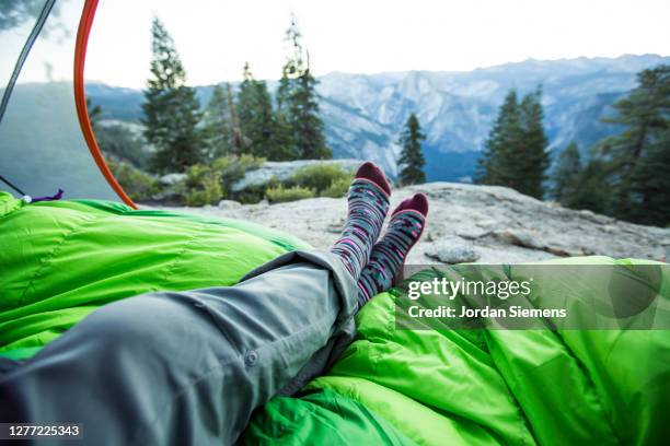 a womans feet insided a tent while camping on a ridge above the yosemite valley. - pés cruzados - fotografias e filmes do acervo