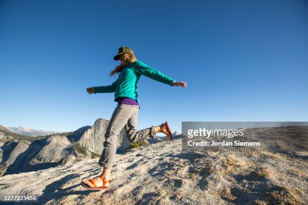 a woman running down a rocky hill with half dome in the distance. - sandales photos et images de collection