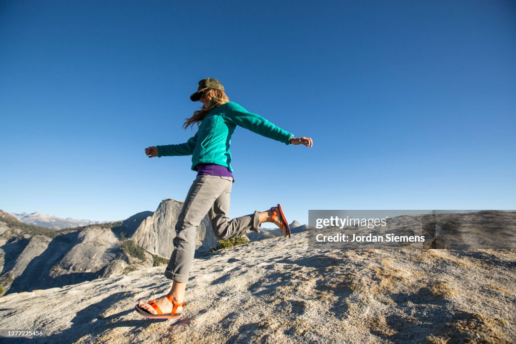 A woman running down a rocky hill with Half Dome in the distance.