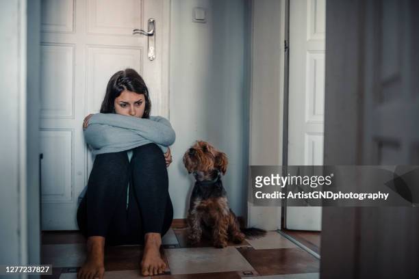 woman with a mental problems is sitting exhausted on the floor with her dog next to her - violence stock pictures, royalty-free photos & images