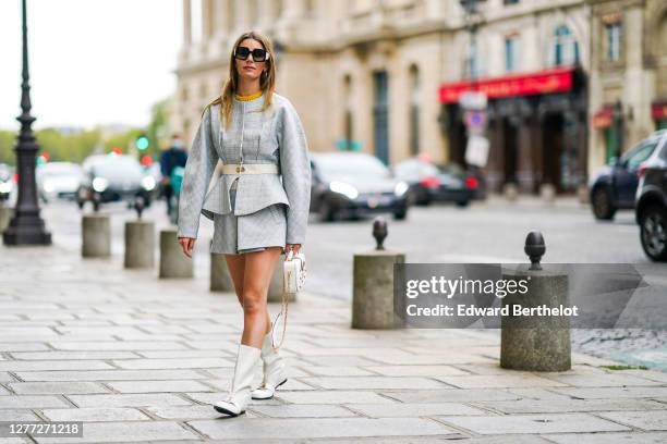 Natalia Verza wears Pucci sunglasses, a pale blue dress with geometric patterns from Lanvin, a Lanvin belt, a Lanvin bag with golden chain and...