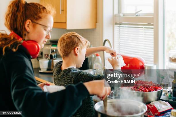 geschwister bereiten rote johannisbeermarmelade zu hause - marmelade machen stock-fotos und bilder