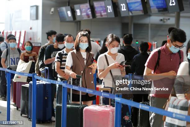 Passengers wearing face masks line up to check-in at Pudong International Airport on September 28, 2020 in Shanghai, China.