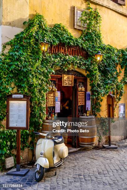 une belle vespa vintage à l’extérieur d’un restaurant typique dans le quartier de trastevere dans le cœur historique de rome - vespa photos et images de collection