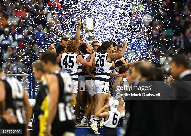 Geelong players celebrate on the dais as Collingwood players leave the ground after the 2011 AFL Grand Final match between the Collingwood Magpies...