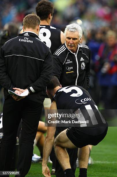 Michael Malthouse coach of the Magpies consoles his assistant Nathan Buckley and captain Nick Maxwell after losing the 2011 AFL Grand Final match...
