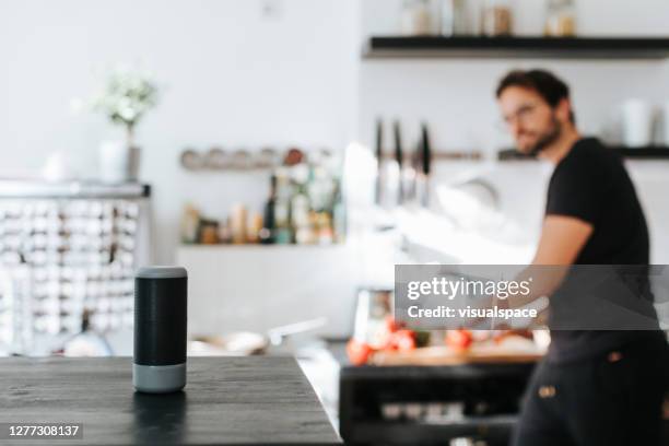 adult man asks cooking advice from smart speaker - smart kitchen stock pictures, royalty-free photos & images