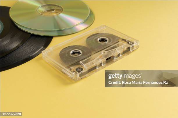 one retro audio cassette tape, vinyl records and compact discs over yellow background. music icons. - compact disc stock pictures, royalty-free photos & images