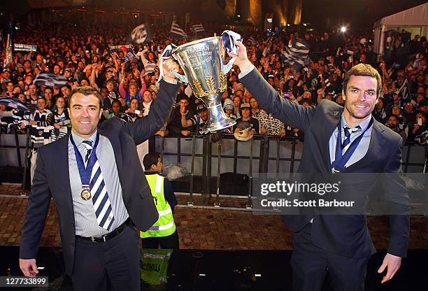 Chris Scott coach and Matthew Scarlett of the Geelong Football Club pose with the Premiership Cup after the 2011 AFL Grand Final match between the...