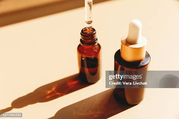 glass bottles for cosmetics with pipette, natural skincare and essential oil on beige background. herbal alternative medicine. copy space. - oil bottle stock pictures, royalty-free photos & images