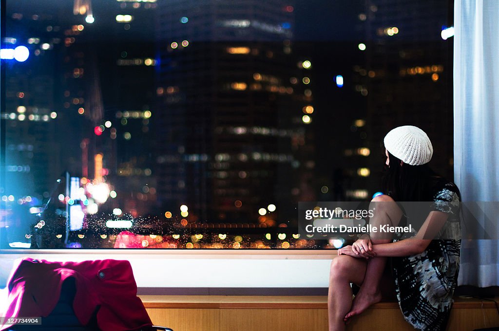 Girl on windowsill watching city below