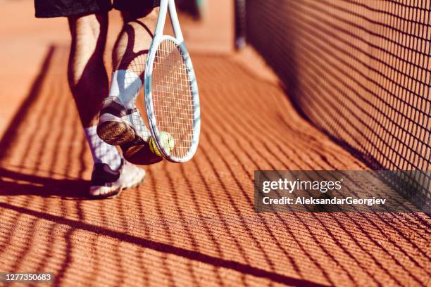 male tennis player picking the ball up with racket and foot - male feet imagens e fotografias de stock