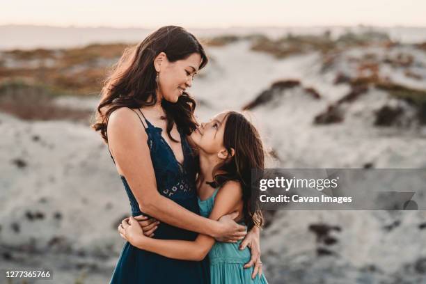 happy mother hugging 8 yr old daughter at the beach - family photo shoot stock pictures, royalty-free photos & images