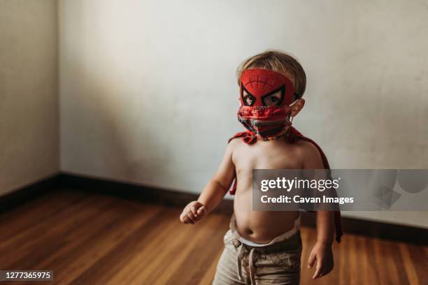 toddler boy walking in halloween costume and face mask - baby superhero stock-fotos und bilder