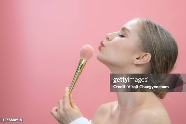 beautiful woman applying make-up with pink pastel background - women pastel stock-fotos und bilder