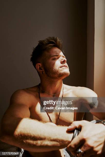 a young man is at home getting the midday sun through the window - wax figure stockfoto's en -beelden