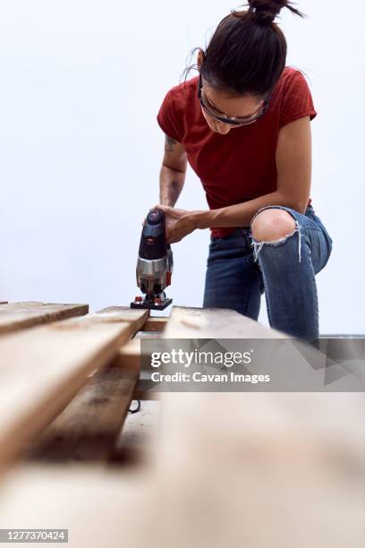 a young woman cutting wooden pallets with a jigsaw - serra tico tico serra elétrica - fotografias e filmes do acervo