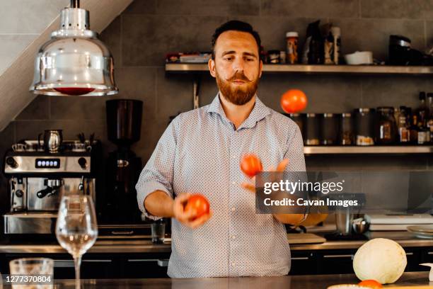 chef juggling tomatoes at restaurant kitchen - jonglieren stock-fotos und bilder