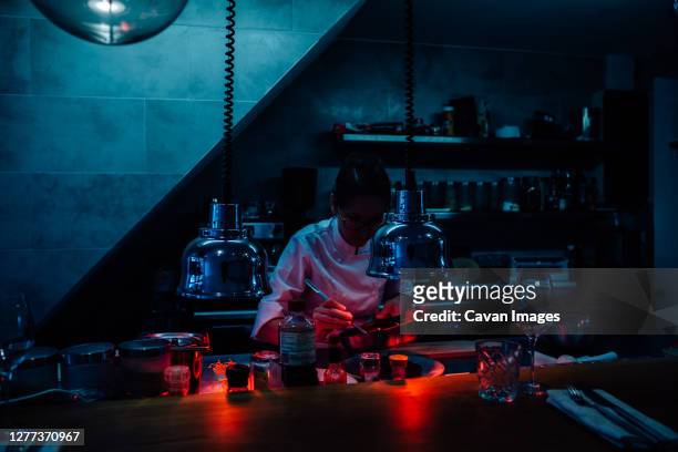 chef decorating food in restaurant kitchen using infrared lamps - dark room foto e immagini stock