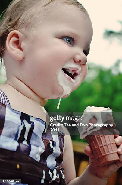 small girl eating ice cream - girl eating messy ice cream cone stock pictures, royalty-free photos & images
