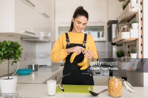 美しい幸せな白人女性は自分自身に健康的な朝食を準備 - banana ストックフォトと画像