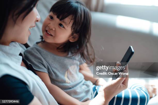 mother and daughter having video call using smart phone together - family mobile ストックフォトと画像