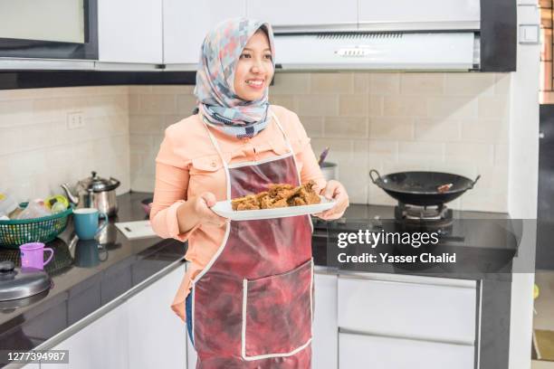 woman serving food in kitchen - muslims prepare for eid in indonesia stock pictures, royalty-free photos & images